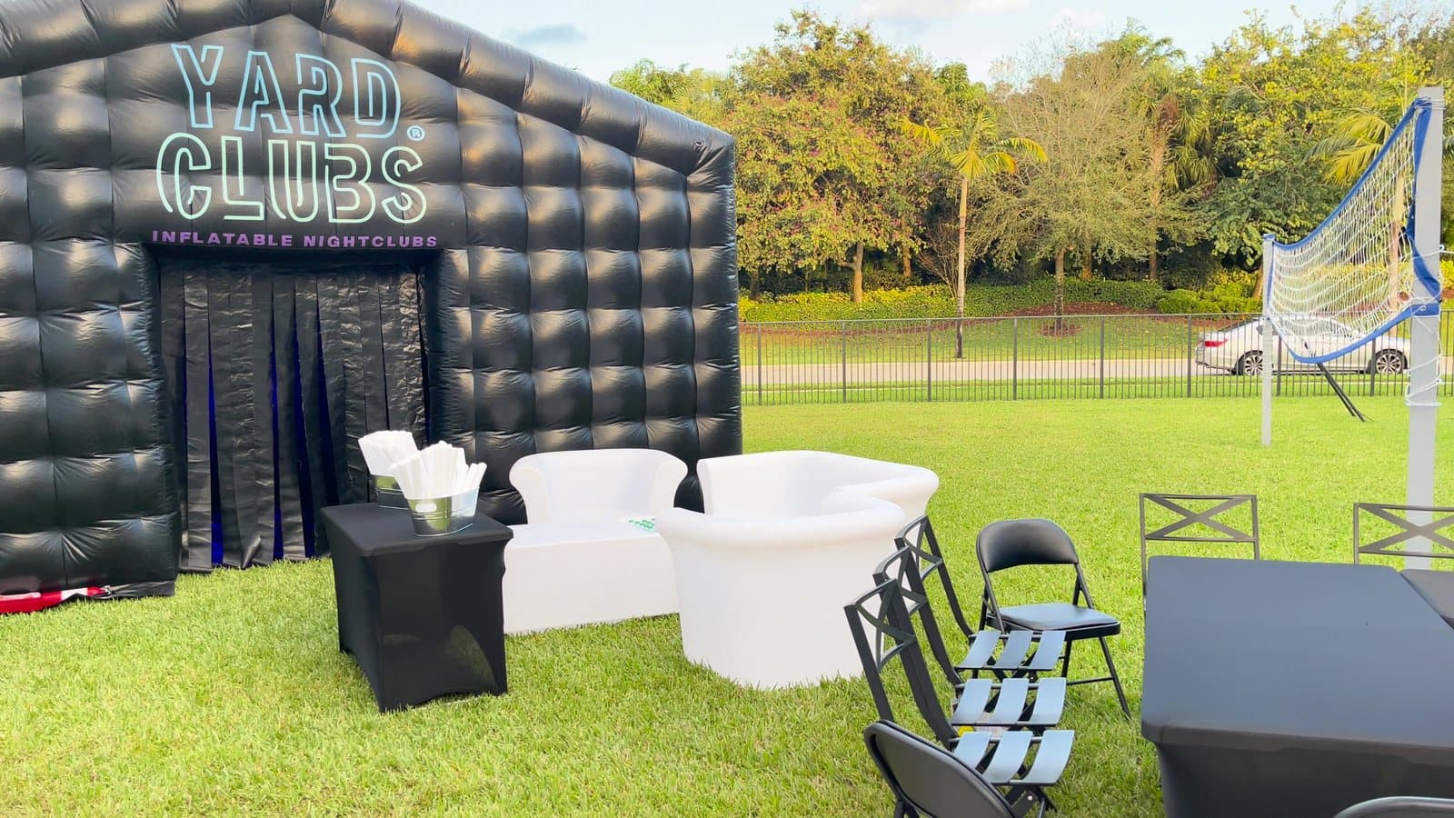 A Yard Clubs inflatable nightclub on a lawn in daylight, a white lounge set out front