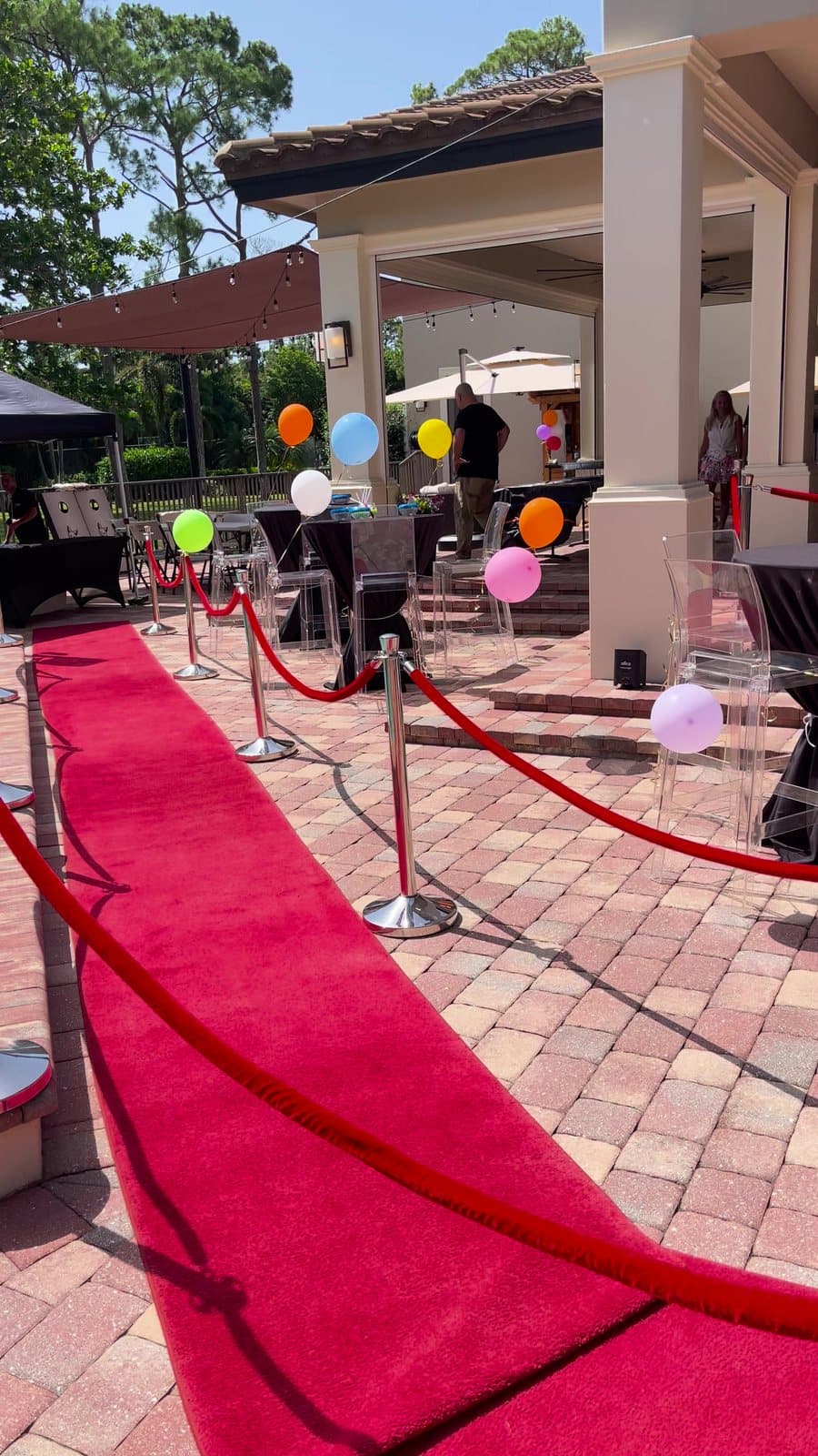 A red carpet and stanchions running along a pool deck to the party