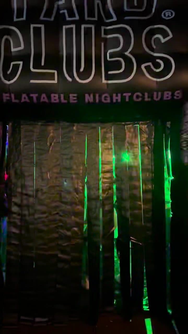 The YARD CLUBS sign over the curtain door, lit green from the party inside