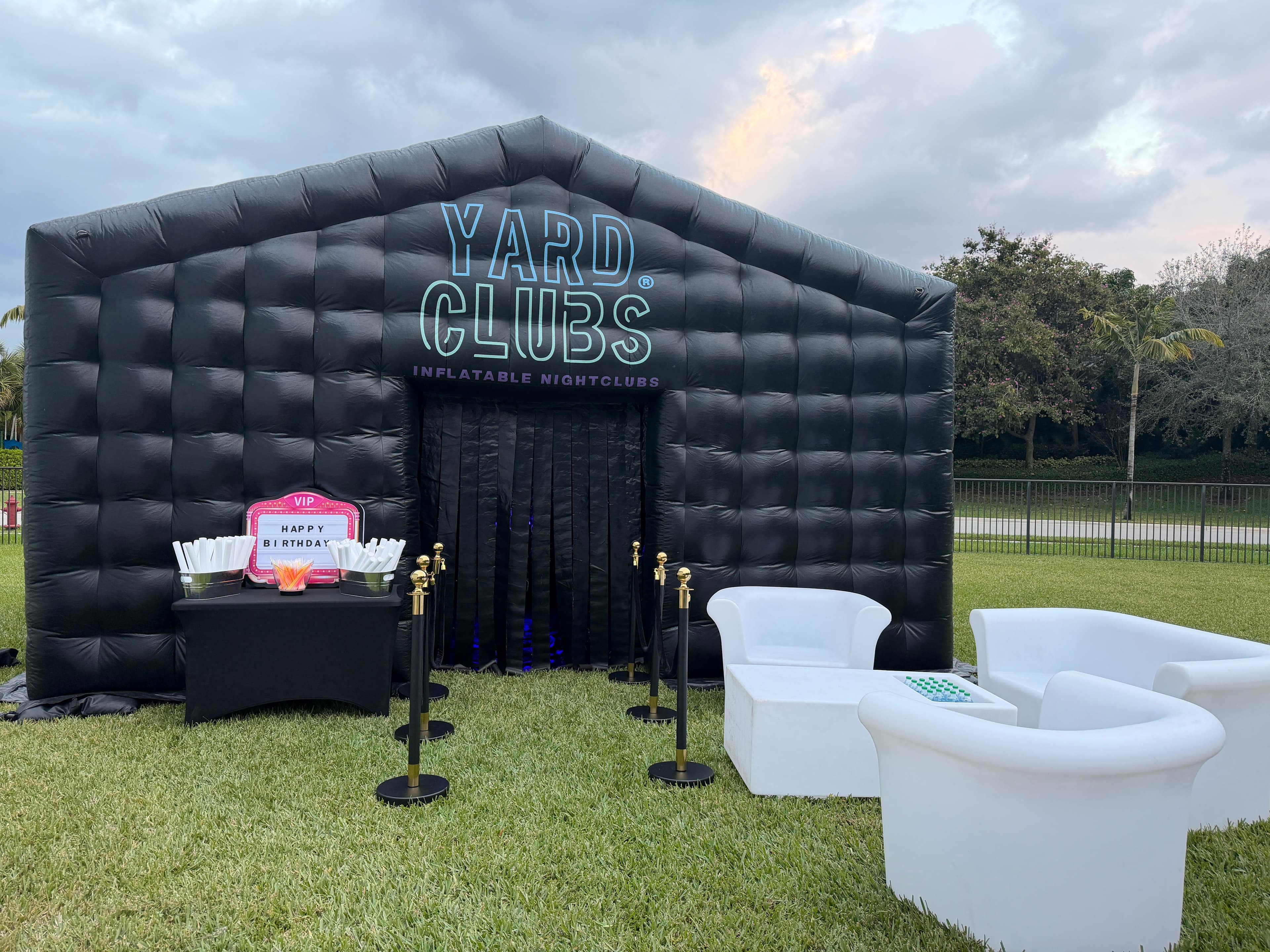 A Yard Clubs nightclub in a backyard with white lounge seating and stanchions